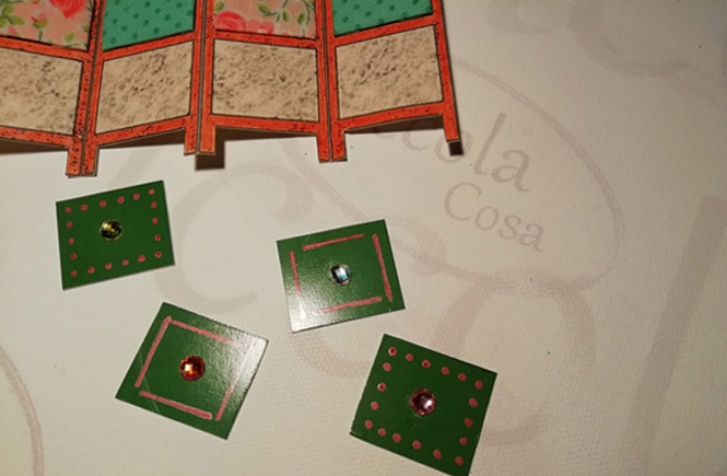 Detalle de los cuadros de cartulina verde con las piezas de cristal pegadas antes de pegarlos al biombo.