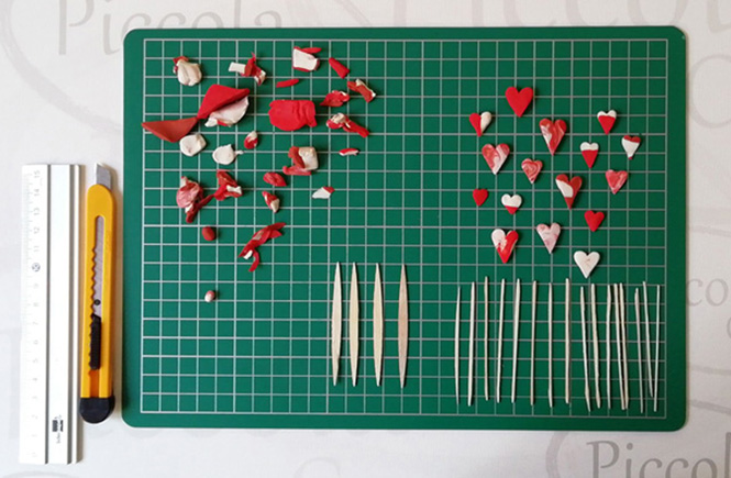 Pequeños corazones de plastilina de color rojo y blanco. Palillos planos cortados para pegar los corazones de plastilina.