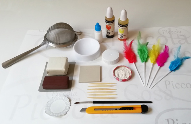 Material to make a "Mona de Pascua": plasticine, white glue, flour, colored feathers, toothpicks, colander, brush, liquid watercolor, ...